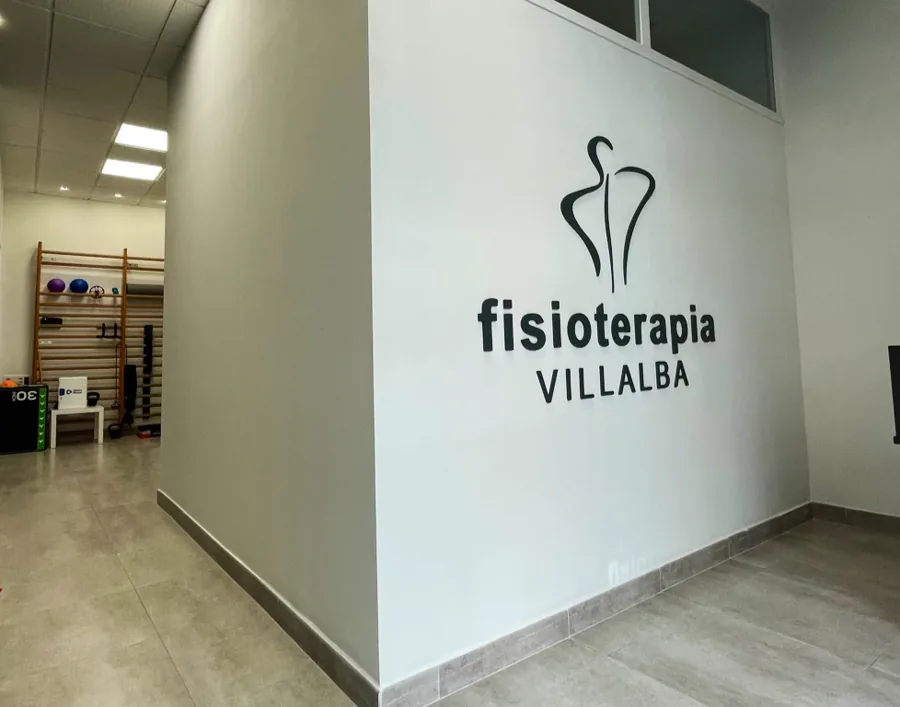 Pared de la clínica con el rótulo de Fisioterapia Villalba y la sala de ejercicio al fondo